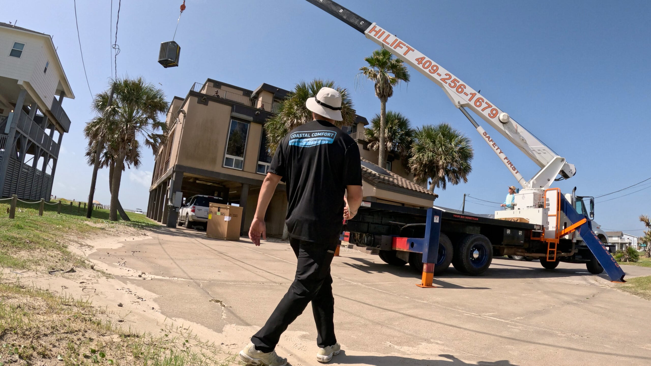 Crane lifting HVAC package unit to rooftop