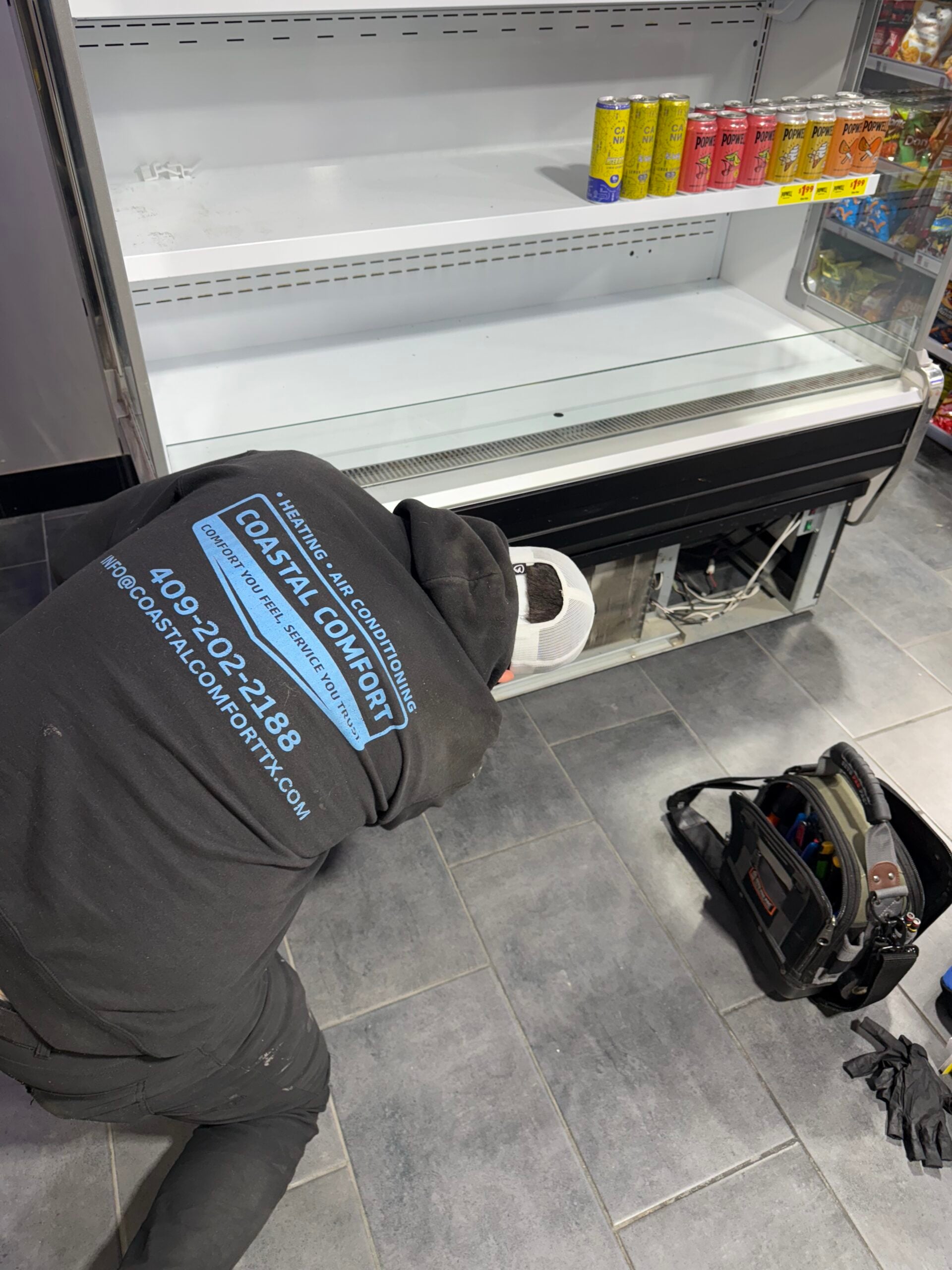 Technician repairing display case compressor