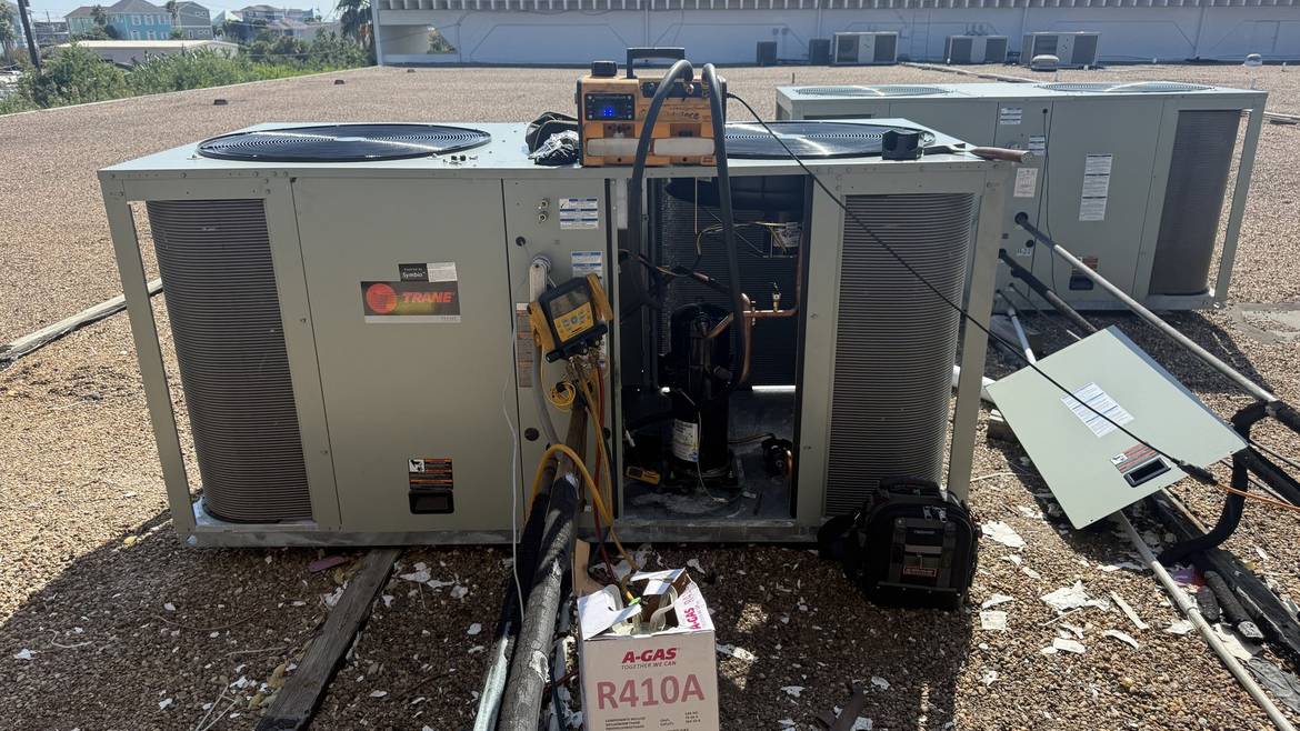 Technician testing a rooftop HVAC unit with gauges during a coastal tune-up